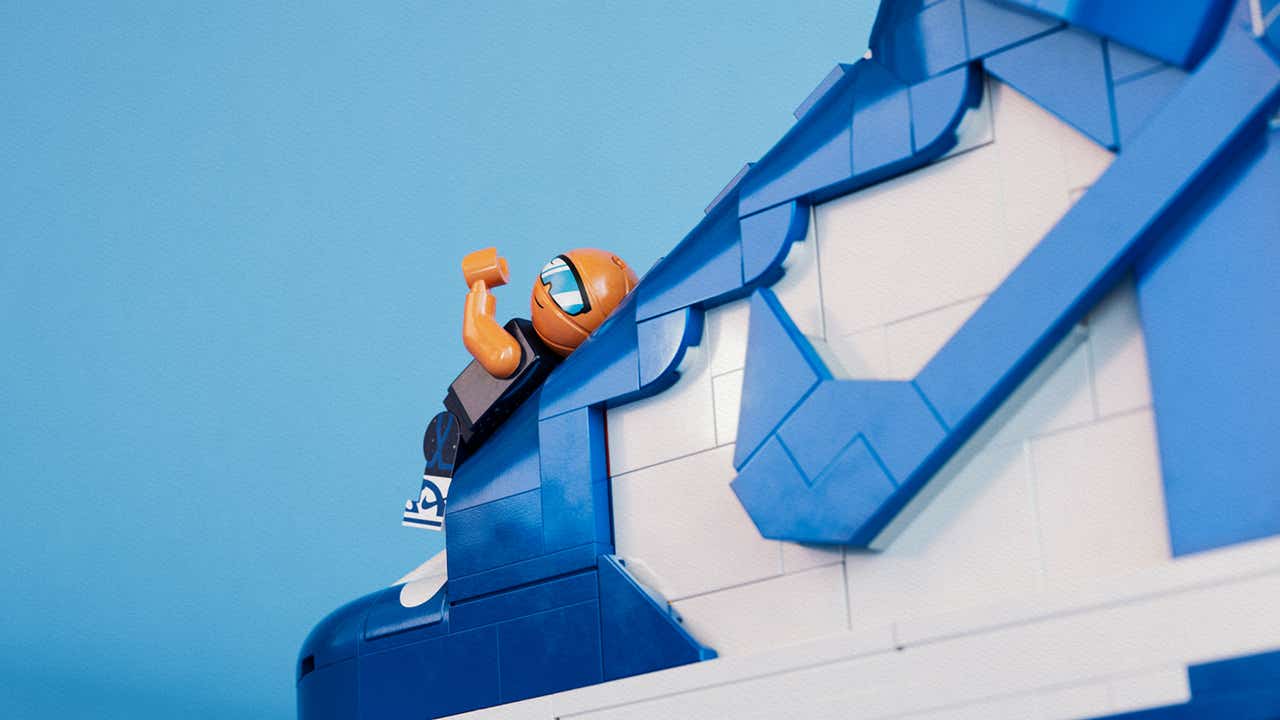 LEGO basketball minifigure climbing a brick-built blue and white Nike Dunk sneaker, showcasing details from the LEGO x Nike collaboration 2025