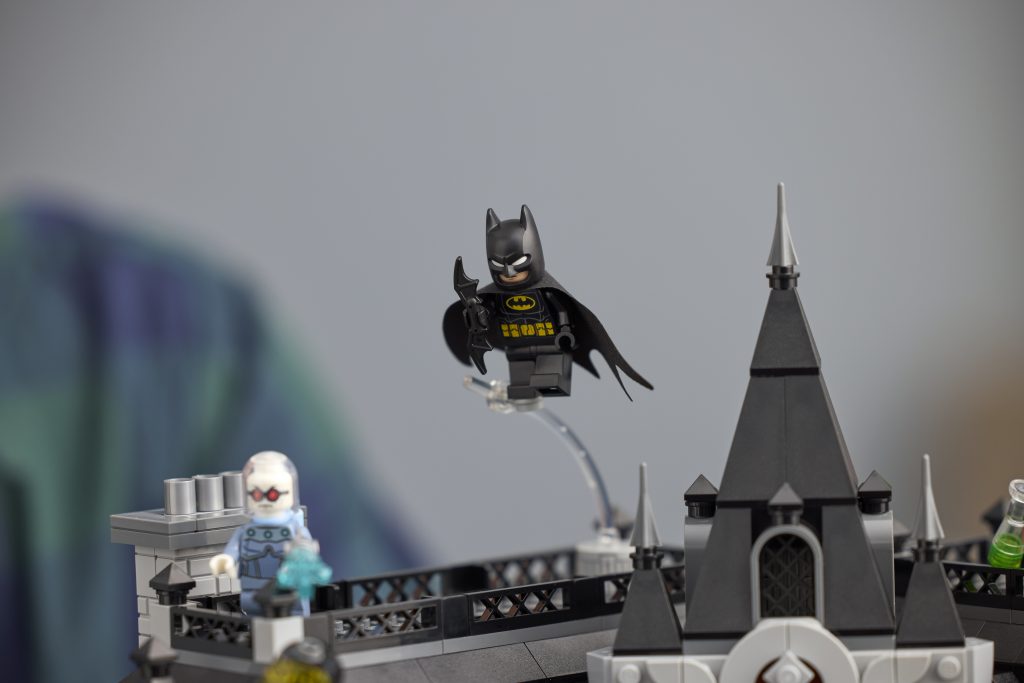 Close-up of classic LEGO Batman minifigure flying above Arkham Asylum rooftop