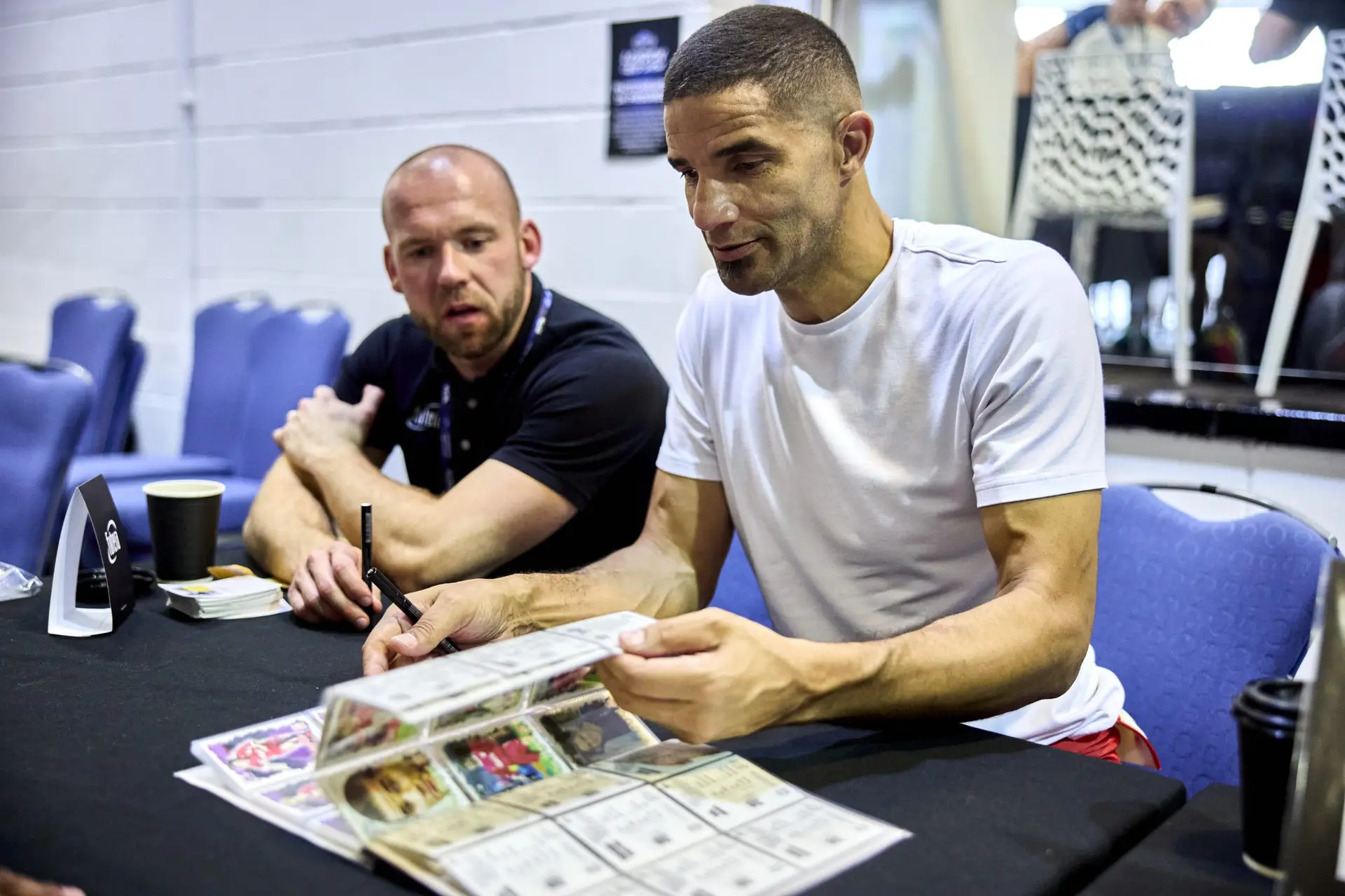 Former professional footballer signs a collector’s album at the London Card Show event table