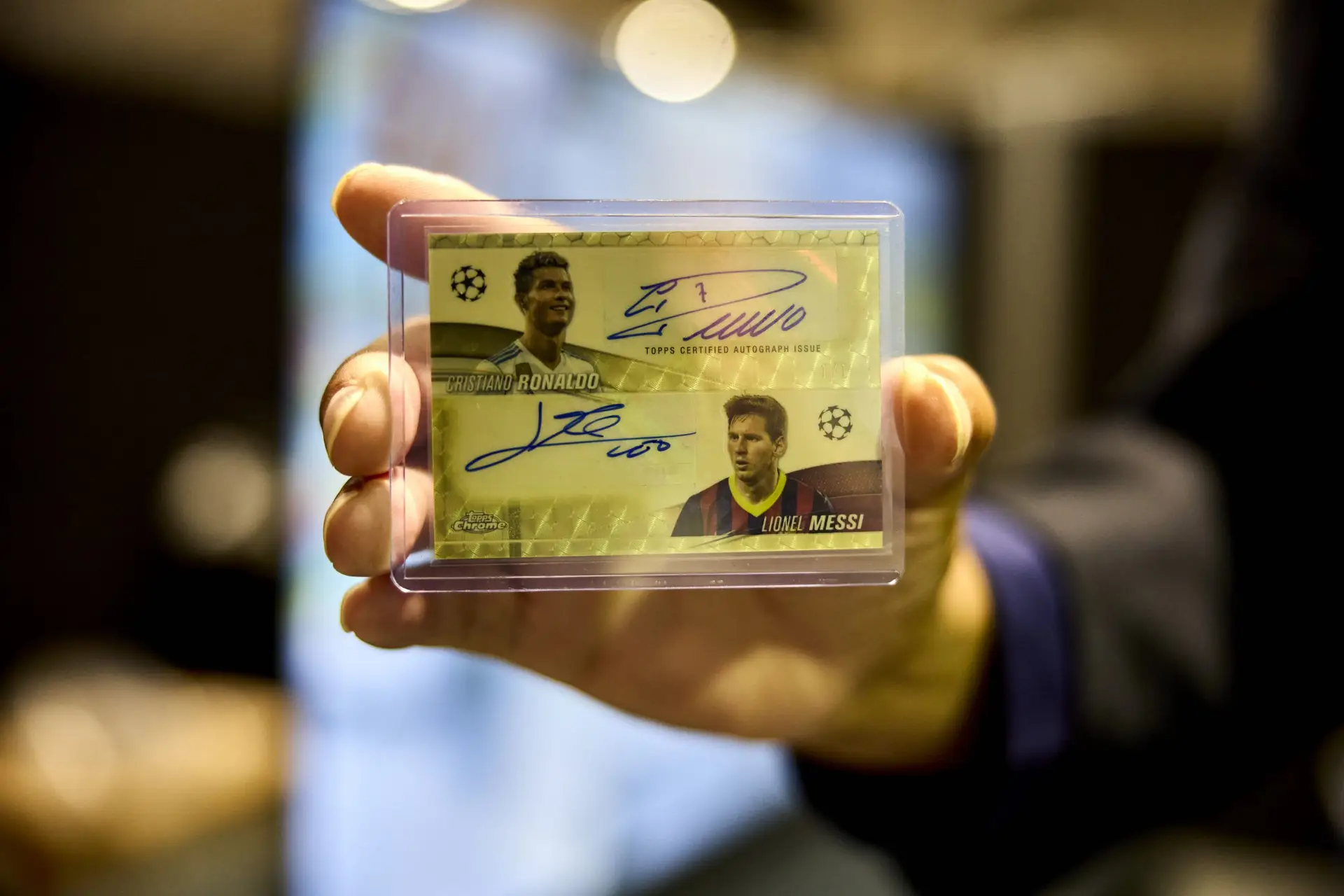 Close-up of a dual autograph Superfractor card featuring Cristiano Ronaldo and Lionel Messi, held by a collector at LCS