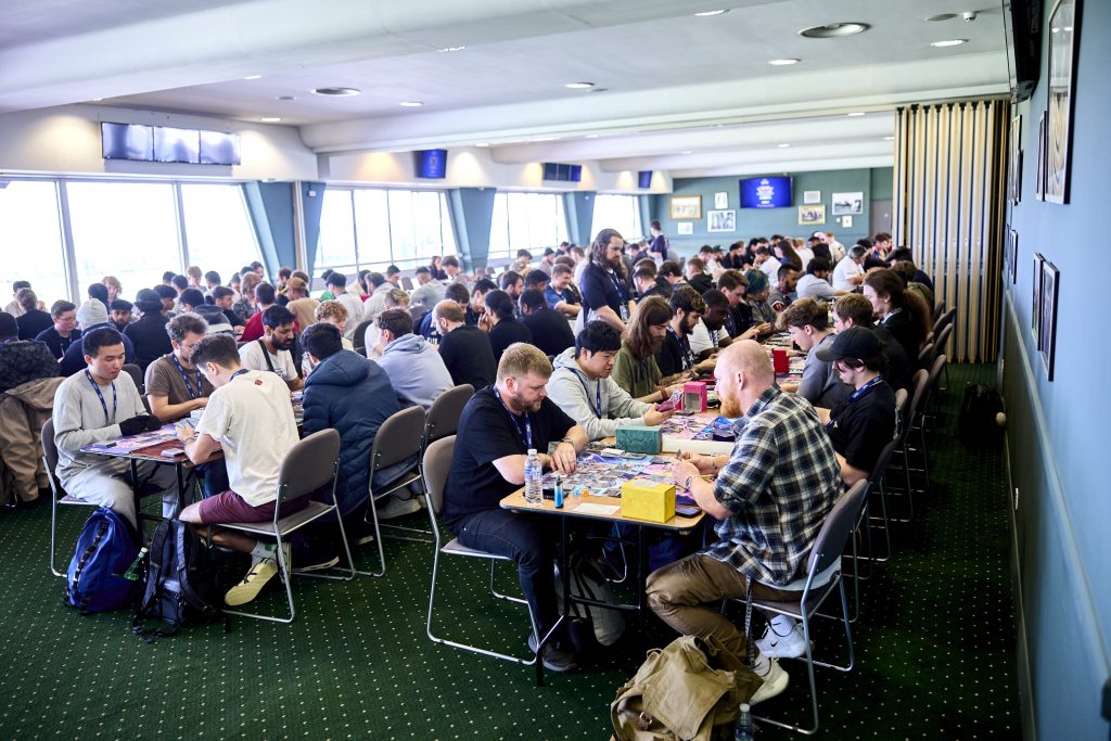 Rows of competitive players battling in Yu-Gi-Oh! and Pokémon Trading Card Game tournaments at the London Card Show, held inside Sandown Park Racecourse