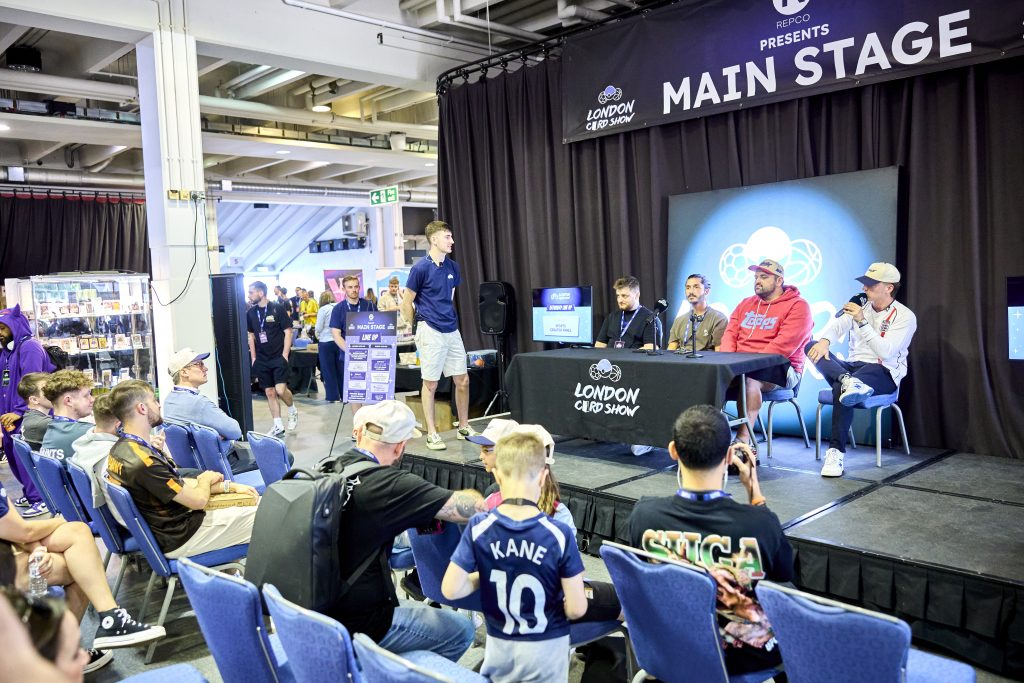 Panel of trading card industry experts including Topps representatives speaking on the London Card Show main stage in front of a seated audience