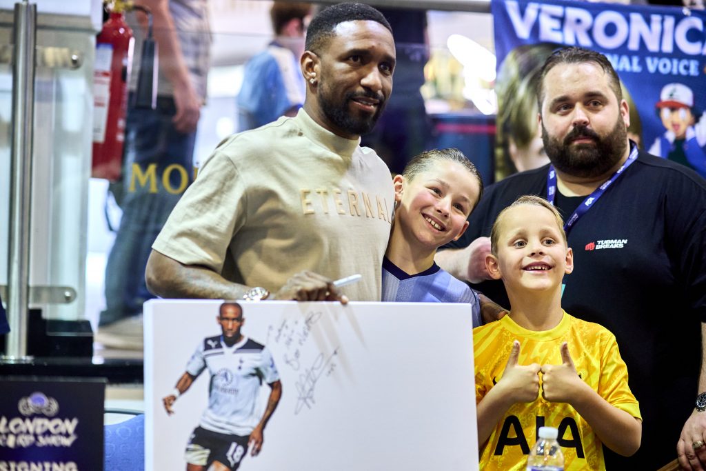 Former Spurs striker Jermain Defoe poses with young fans and a signed photo at the London Card Show, part of the special guest signing sessions