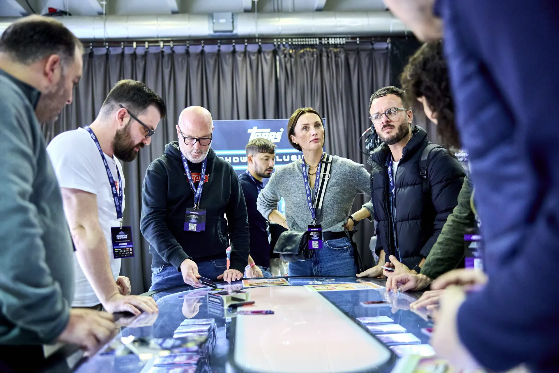 Group of attendees interacting with Topps showcase display at London Card Show